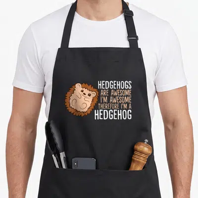 Therefore hedgehog mom apron - Cartoon hedgehog with stacked text HEDGEHOGS ARE AWESOME in brown and orange — shown on a black cotton canvas apron against a white background