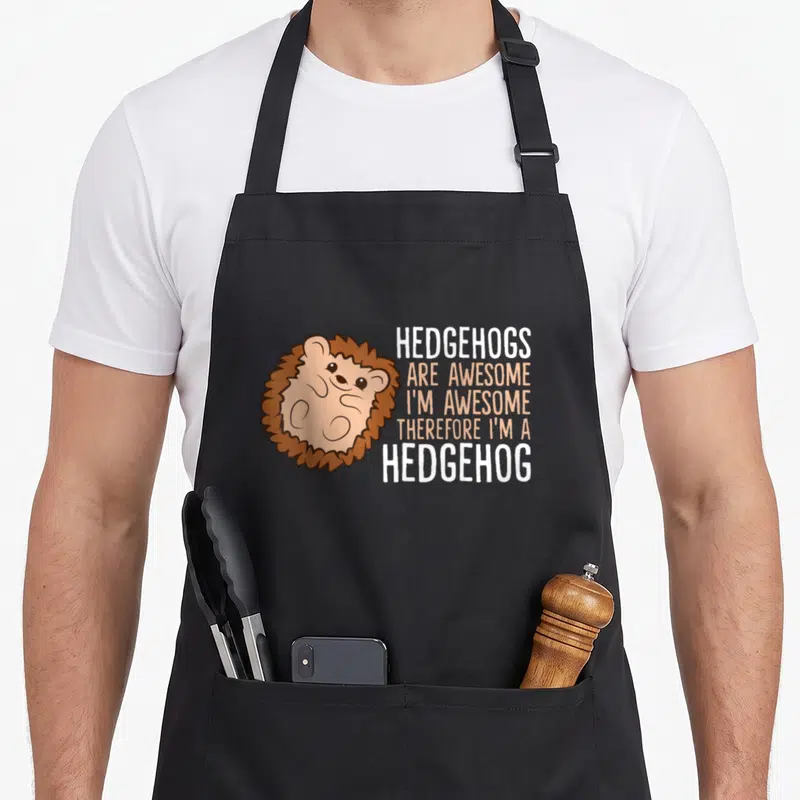 Therefore hedgehog mom apron - Cartoon hedgehog with stacked text HEDGEHOGS ARE AWESOME in brown and orange — shown on a black cotton canvas apron against a white background