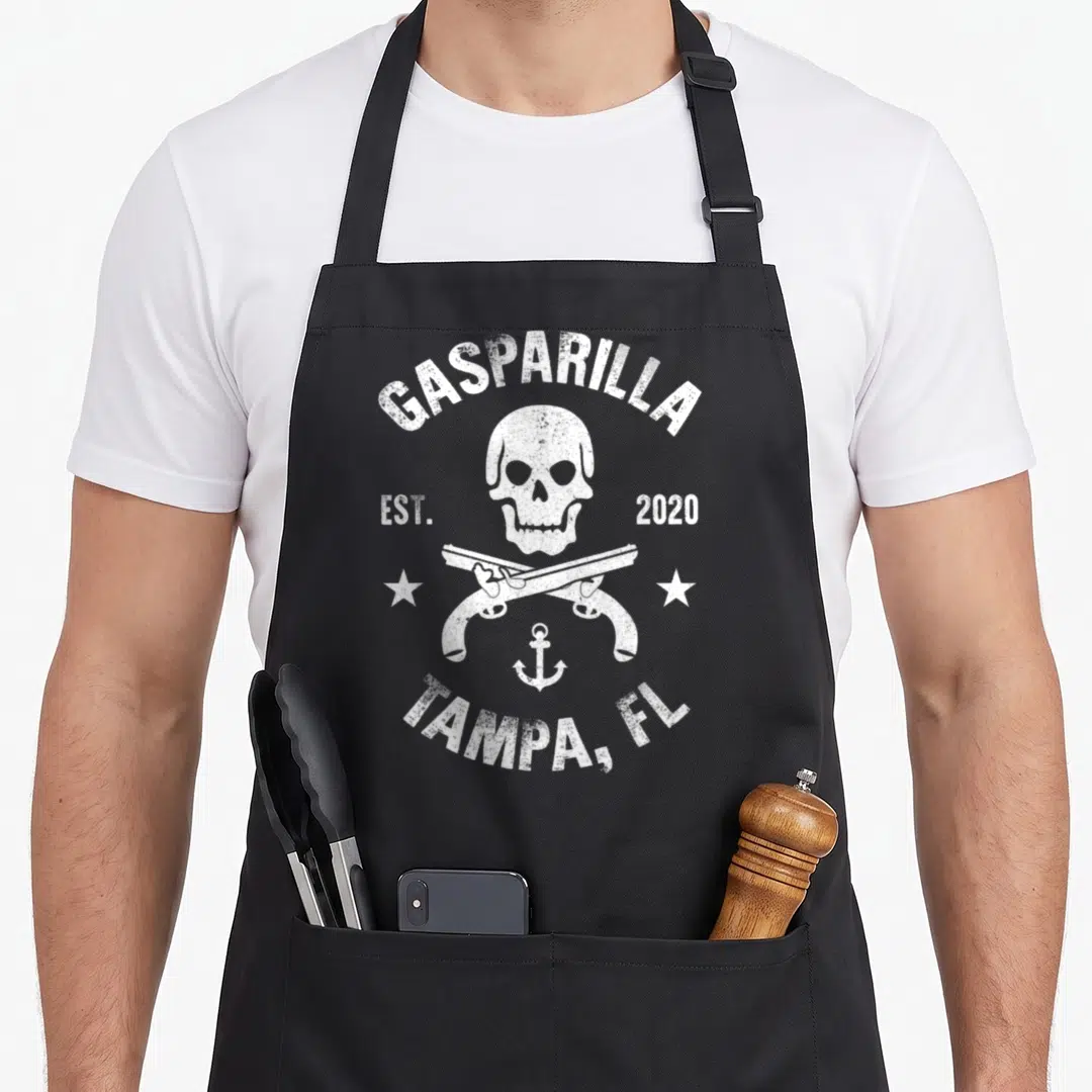 Gasparilla skull apron - White distressed skull crossed pistols anchor GASPARILLA 2020 TAMPA FL text — shown on a black cotton canvas apron against a white background