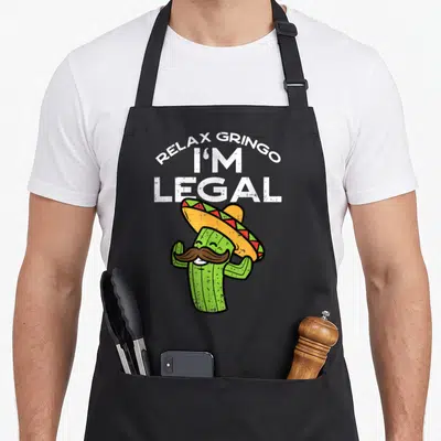 Relax mexican apron - Cartoon cactus with sombrero and mustache under Relax Gringo Im Legal text — shown on a black cotton canvas apron against a white background