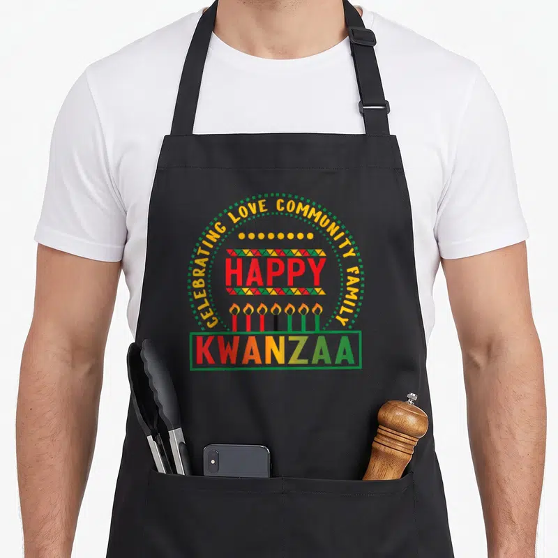 Marias modern apron - Kwanzaa typography design with seven candles and arch text CELEBRATING LOVE COMMUNITY FAMILY — shown on a black cotton canvas apron against a white background