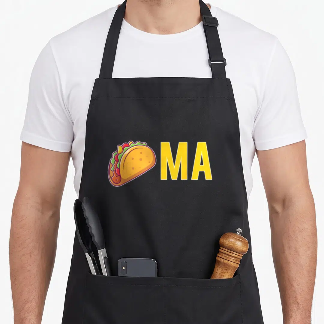 Themed taco apron - Cartoon taco next to yellow MA text on black fabric — shown on a black cotton canvas apron against a white background
