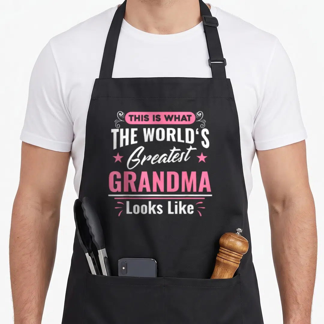 Grandma worlds greatest dad apron - Stacked white and pink text reading This Is What The World's Greatest Grandma Looks — shown on a black cotton canvas apron against a white background