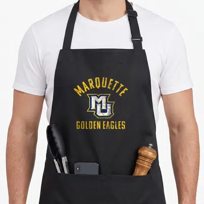 Golden eagles apron - Distressed Marquette MU logo with yellow text on black background — shown on a black cotton canvas apron against a white background