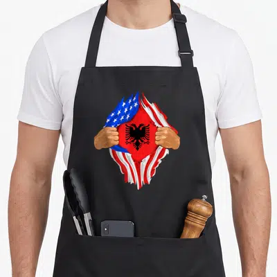 Albanian blood apron - Two hands tear USA flag to reveal red Albanian flag with black double-headed eagle — shown on a black cotton canvas apron against a white background