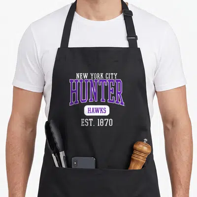 College hunter apron - Purple and white text reading NEW YORK CITY HUNTER HAWKS EST 1870 on black fabric — shown on a black cotton canvas apron against a white background