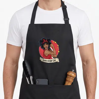 Trini trinidadian girl apron - Cartoon woman in red circle with yellow stars and cream ribbon reading TRINIDADIAN GIRL — shown on a black cotton canvas apron against a white background