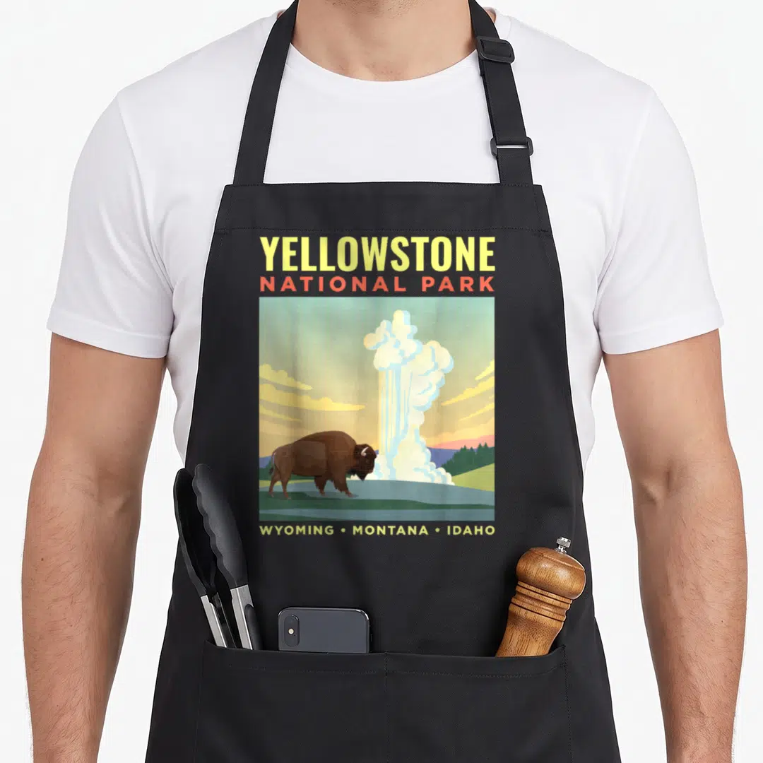 Park us aprons - Retro Yellowstone bison and geyser illustration with state names in yellow and orange text — shown on a black cotton canvas apron against a white background