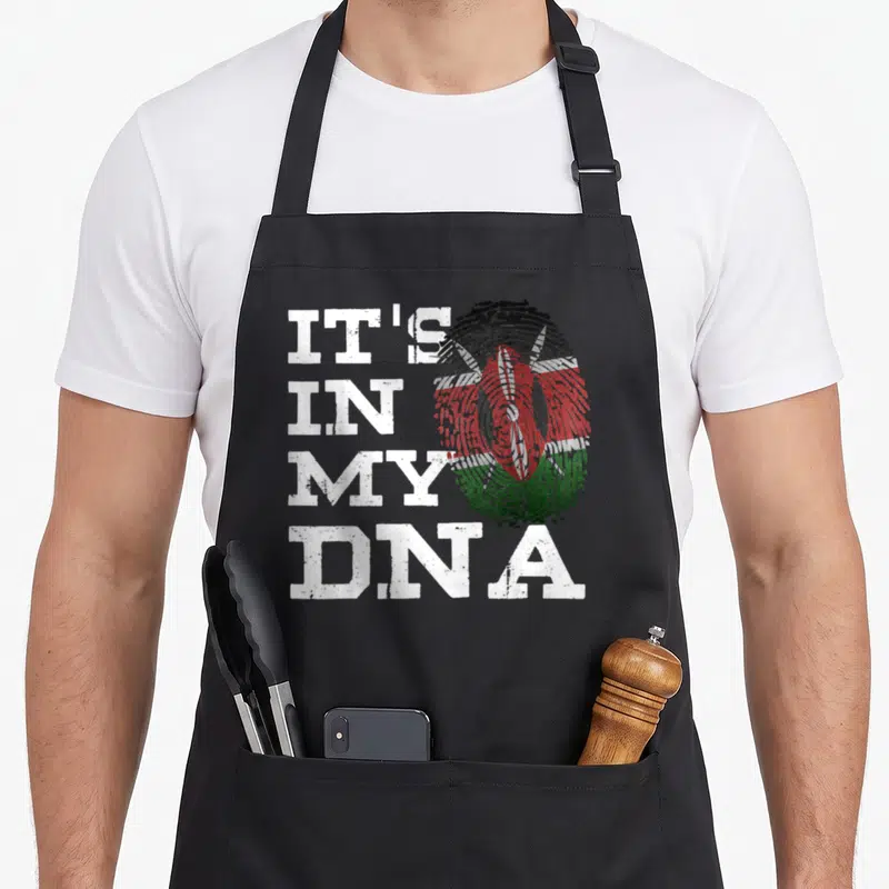 Fingerprint kenyan boy apron - Stacked white text IT'S IN MY DNA next to a distressed fingerprint containing the Kenyan — shown on a black cotton canvas apron against a white background