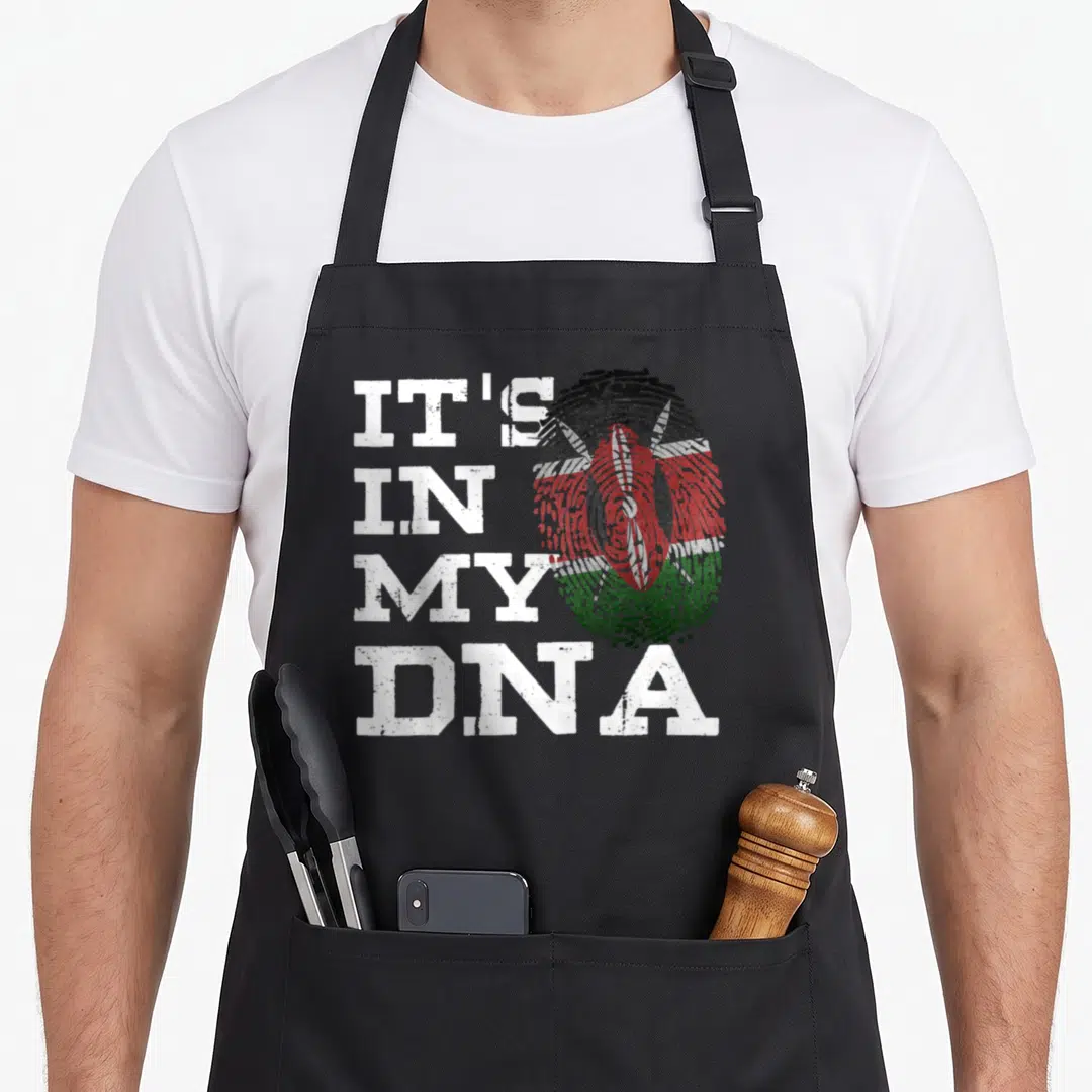 Fingerprint kenyan boy apron - Stacked white text IT'S IN MY DNA next to a distressed fingerprint containing the Kenyan — shown on a black cotton canvas apron against a white background