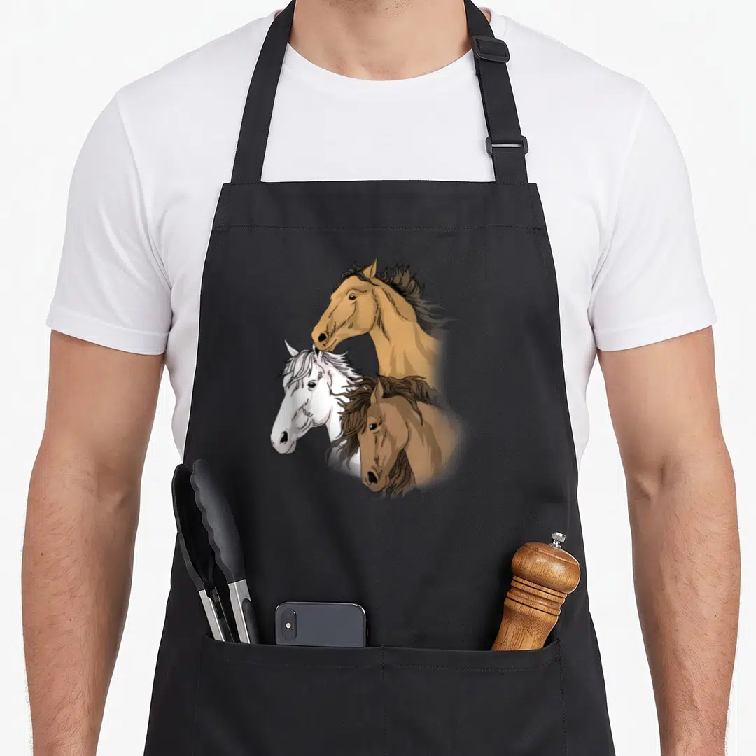 Retro riding horse apron - Three cartoon horse heads in tan, white, and brown clustered together — shown on a black cotton canvas apron against a white background