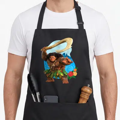 Maui tropical print aprons - Maui holding a fishhook above his head with flowers and mountains in blue, brown, tan — shown on a black cotton canvas apron against a white background