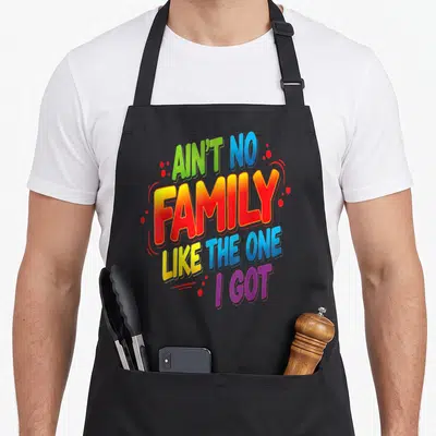 Funny family reunion aprons for grilling - Stacked colorful gradient text reading AIN'T NO FAMILY LIKE THE ONE I GOT — shown on a black cotton canvas apron against a white background