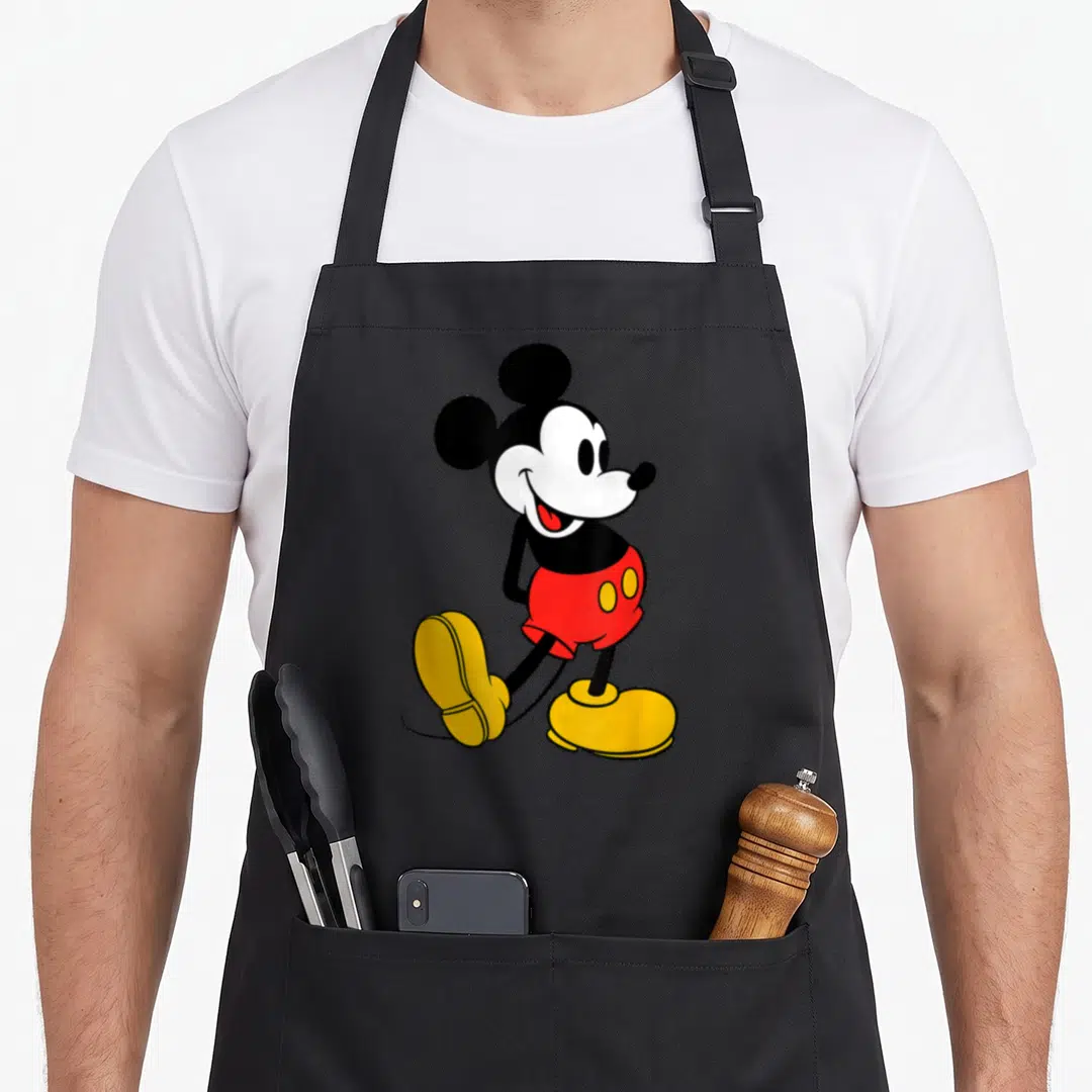 Vintage crazy mouse man apron - Cartoon mouse in red shorts yellow shoes black white red color scheme centered walk pose — shown on a black cotton canvas apron against a white background