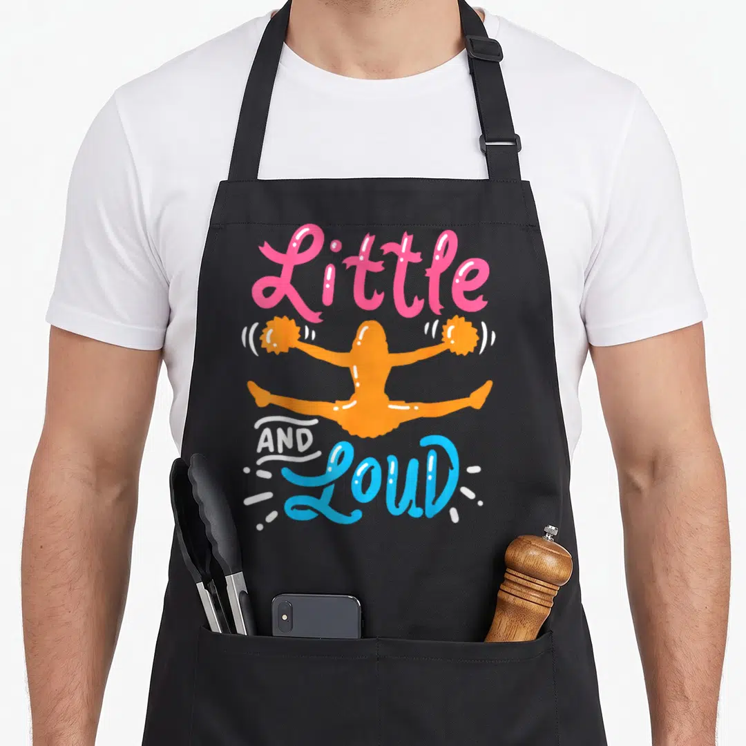 Cheerleading split apron - Little AND LOUD text surrounding an orange cartoon cheerleader doing a split jump in pink — shown on a black cotton canvas apron against a white background