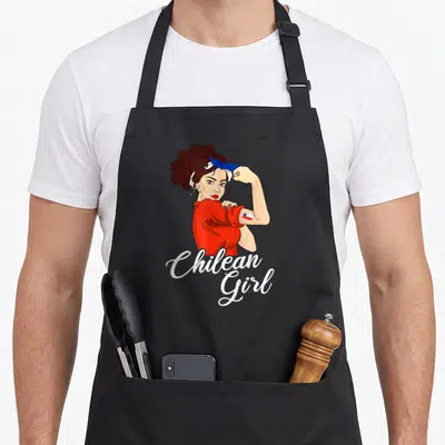 Funny chilean chile apron - Cartoon woman flexing arm with flag tattoo above stacked Chilean Girl text in red white blue — shown on a black cotton canvas apron against a white background