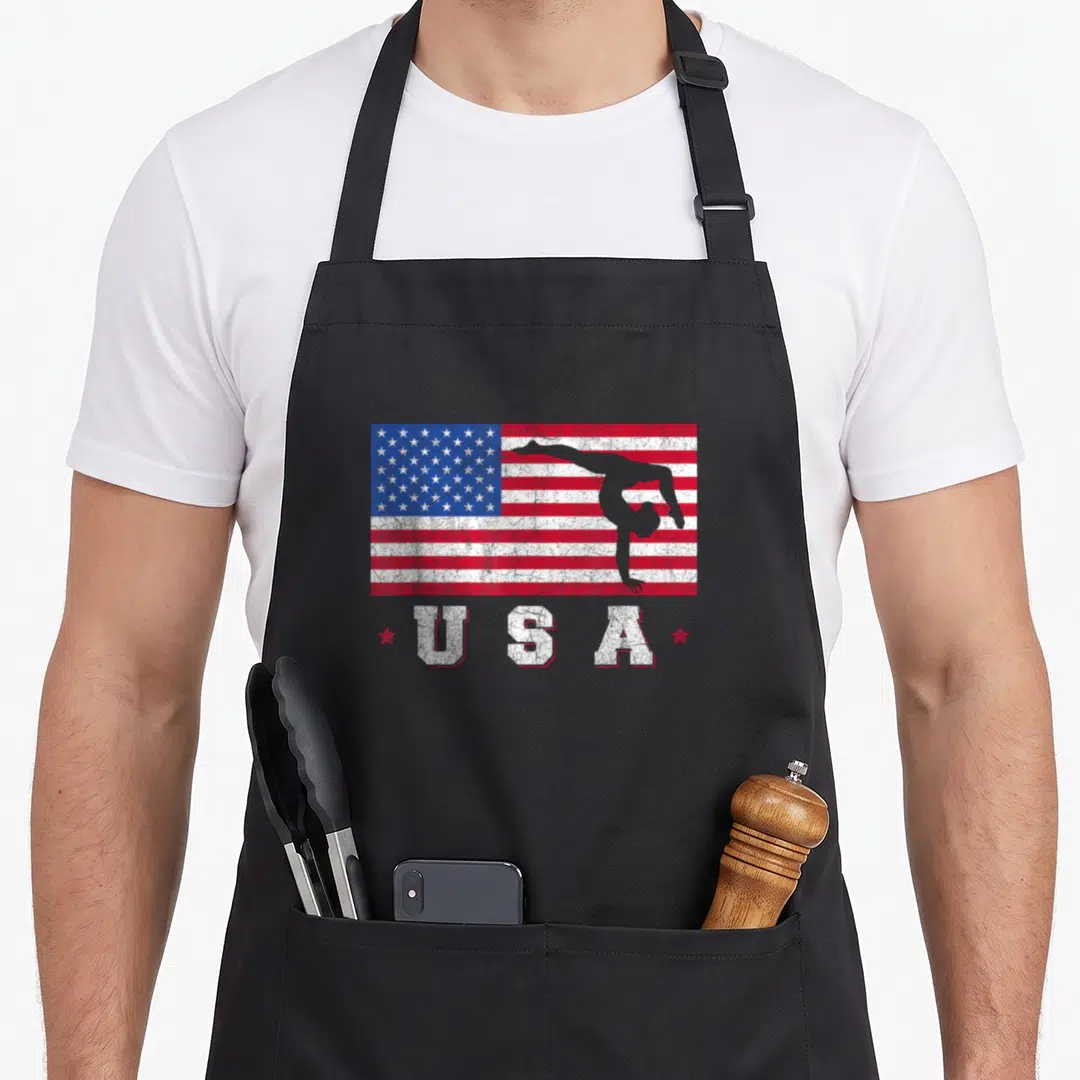 Sport american flag apron - Distressed USA flag with grey gymnast backbend silhouette and two red stars below — shown on a black cotton canvas apron against a white background