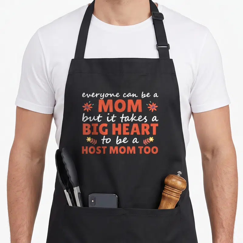 Host student aprons - Everyone can be a mom but it takes a big heart to be a host mom too text art — shown on a black cotton canvas apron against a white background