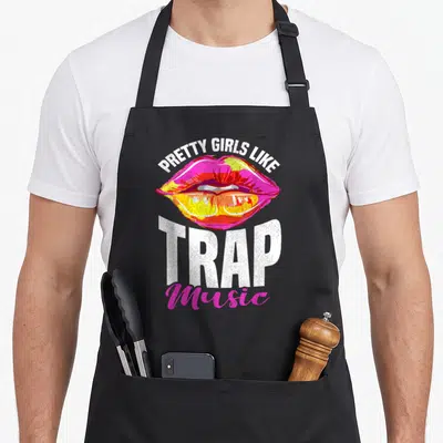 Trap pretty apron - Retro pink lips with pretty girls like trap music text — shown on a black cotton canvas apron against a white background