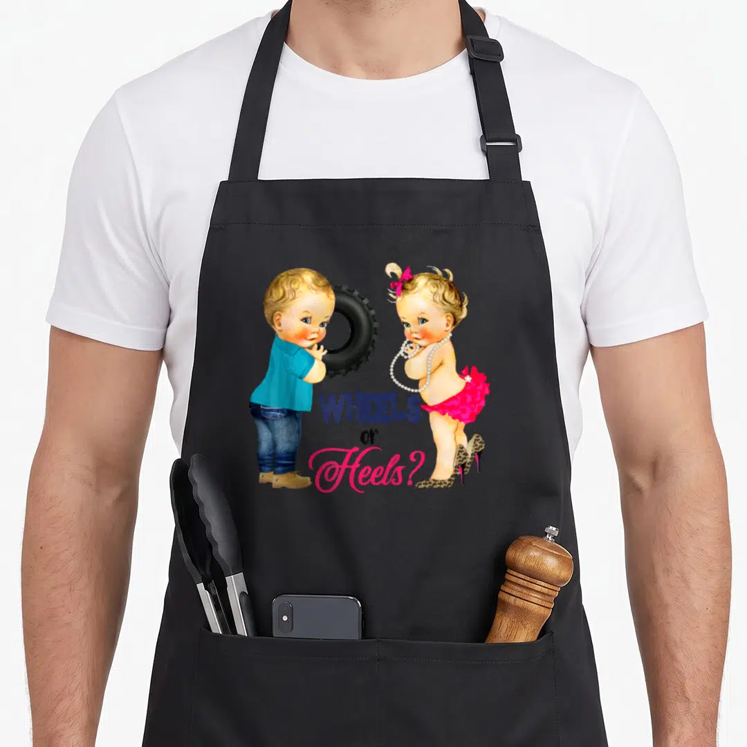 Baby wheel apron - Cartoon boy with tire and girl in leopard heels with WHEELS or Heels text — shown on a black cotton canvas apron against a white background