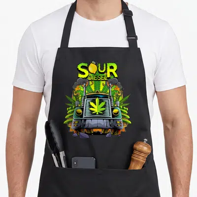 Weed truck apron - SOUR DIESEL text with lemon, cartoon truck, cannabis leaves, smoke, broken rocks — shown on a black cotton canvas apron against a white background