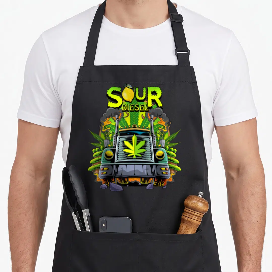 Weed truck apron - SOUR DIESEL text with lemon, cartoon truck, cannabis leaves, smoke, broken rocks — shown on a black cotton canvas apron against a white background