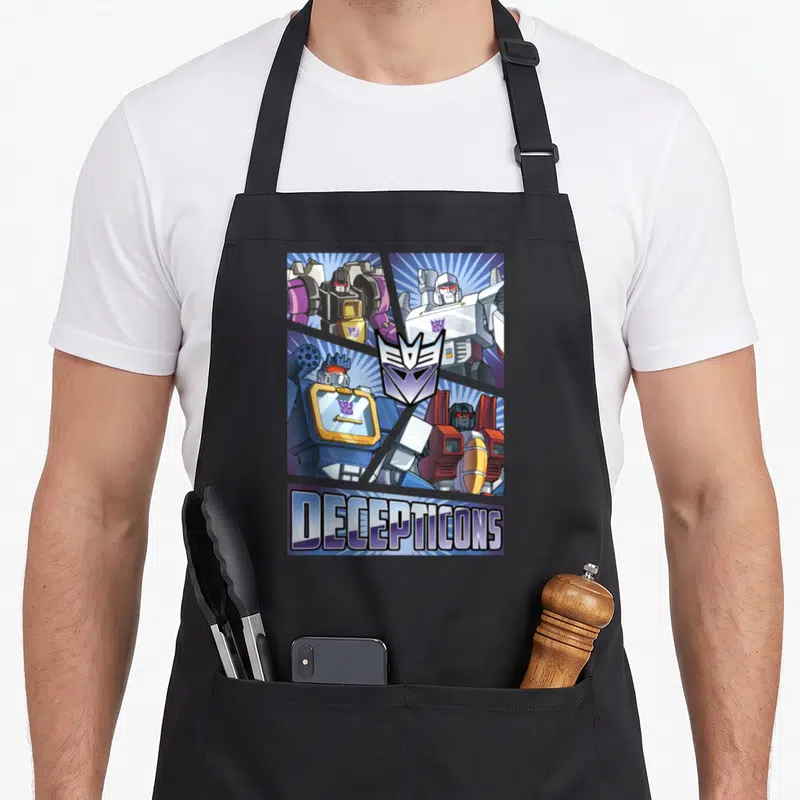 Cut transformer apron - Four robots in grid with purple Decepticon logo and bottom text banner — shown on a black cotton canvas apron against a white background