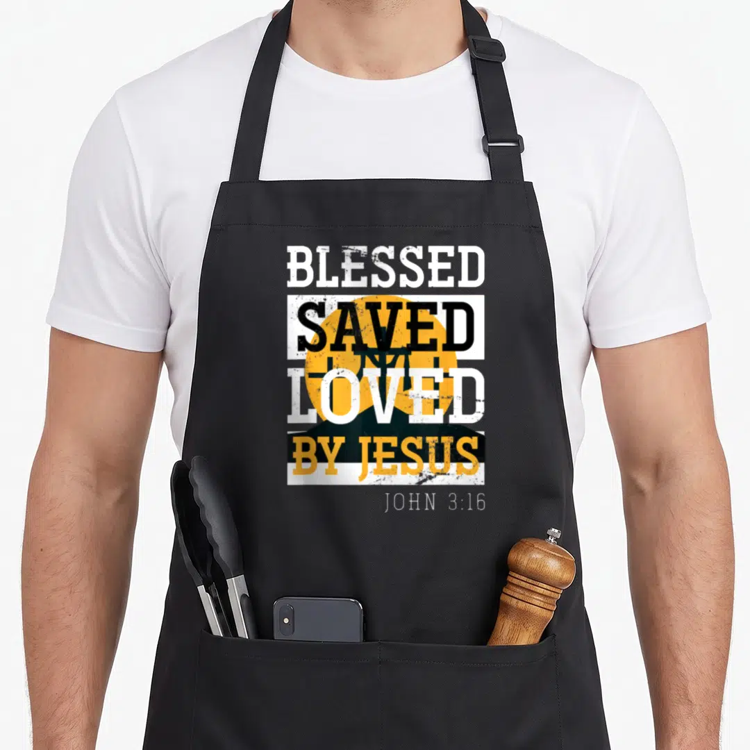 Jesus lord cross apron - Stacked BLESSED SAVED LOVED BY JESUS text over black cross and yellow sun with John 3:16 — shown on a black cotton canvas apron against a white background