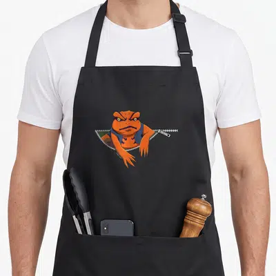 Gamakichi anime apron - Orange frog emerging from zipper pocket with JUMP text on pull tab — shown on a black cotton canvas apron against a white background
