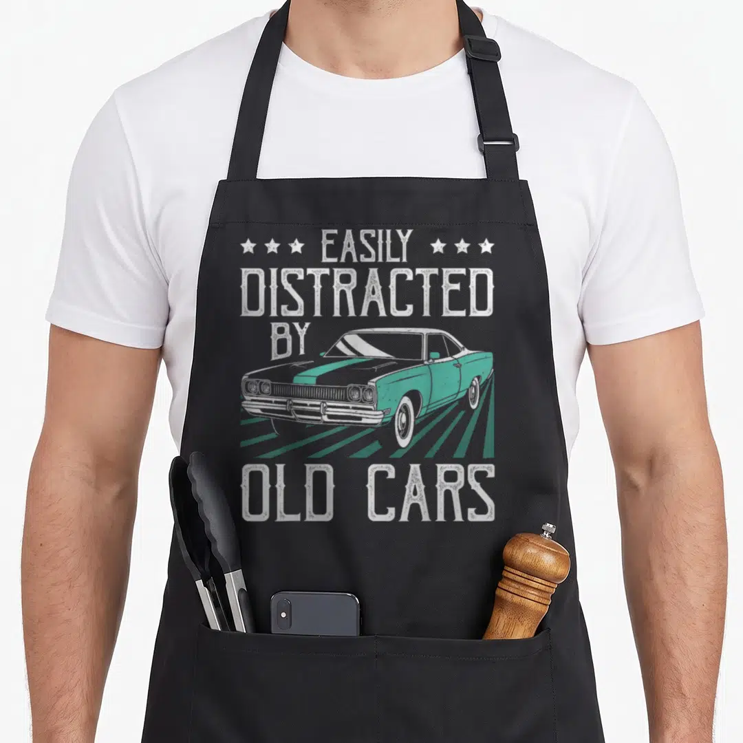 Distracted car apron - EASILY DISTRACTED BY OLD CARS text around teal striped vintage car with white stars — shown on a black cotton canvas apron against a white background