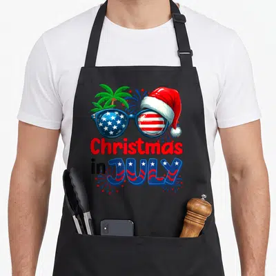 Summer christmas santa apron - Sunglasses with Santa hat and Christmas in JULY text with palm trees — shown on a black cotton canvas apron against a white background