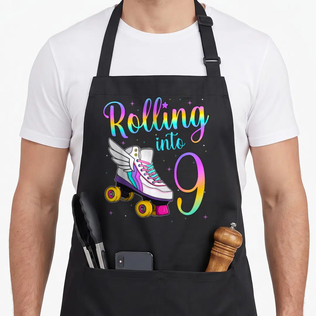 Skate turning apron - Rolling into 9 text with winged roller skate and rainbow gradient stars — shown on a black cotton canvas apron against a white background