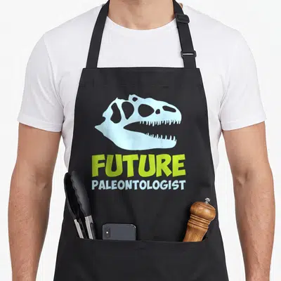 Paleontologist dinosaur science apron - Light blue dinosaur skull above Future Paleontologist text in lime green — shown on a black cotton canvas apron against a white background