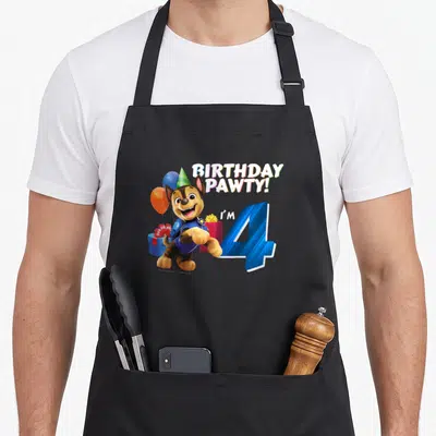 Chase bday apron - Cartoon dog wearing hat next to blue number 4 and Birthday Pawty text — shown on a black cotton canvas apron against a white background