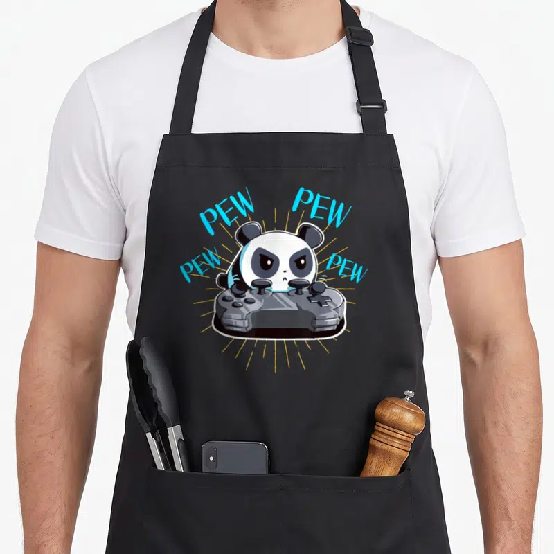 Gamer dad mode apron - Cartoon panda holding grey controller with light blue PEW text and yellow lines — shown on a black cotton canvas apron against a white background