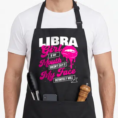 Libra astrology birthday apron - Pink lips and white text reading Libra Girl If My Mouth Doesn't Say It My Face — shown on a black cotton canvas apron against a white background