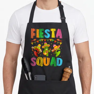 Fiesta of squad apron - Cartoon chili, cactus, and pepper wearing sombreros holding maracas under colorful FIESTA SQUAD — shown on a black cotton canvas apron against a white background