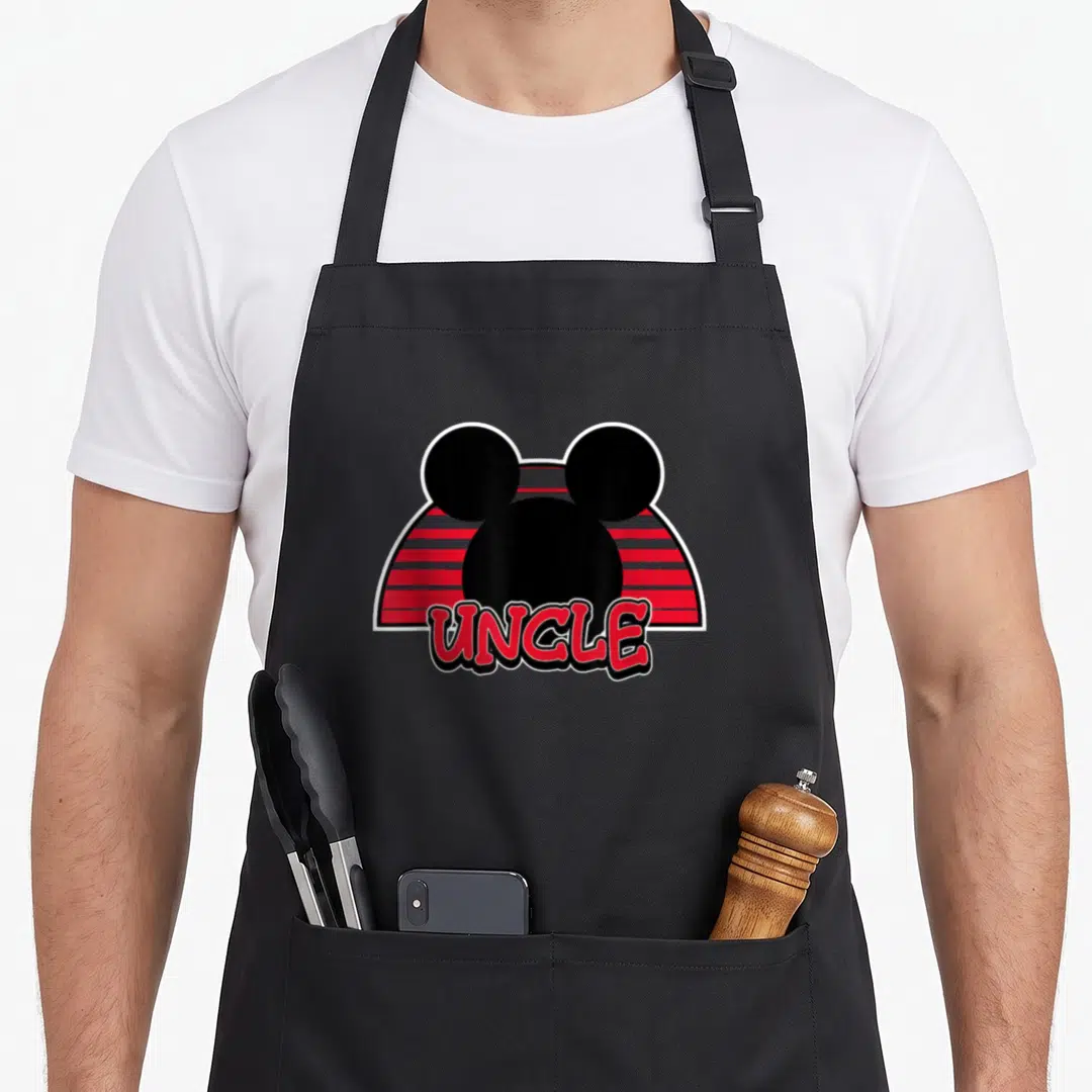 Uncle summer birthday apron - Black Mickey Mouse head silhouette over red grey stripes with UNCLE text in cartoon font — shown on a black cotton canvas apron against a white background