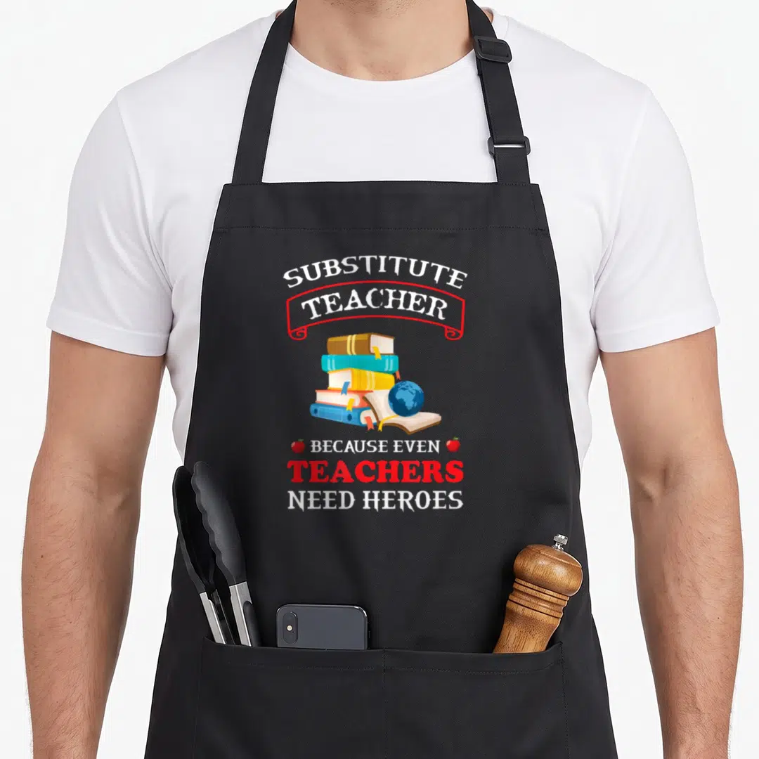 Substitute even teacher apron - Stack of books and globe with Substitute Teacher Because Even Teachers Need Heroes text — shown on a black cotton canvas apron against a white background