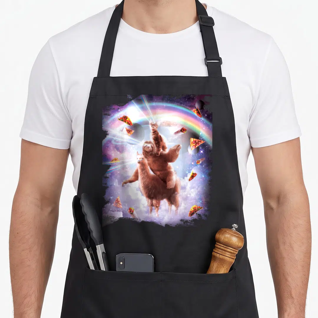 Laser space cat apron - Cat sloth llama stack in space with laser beams, pizza, tacos, rainbow, and clouds — shown on a black cotton canvas apron against a white background