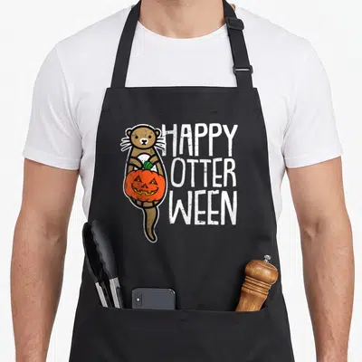 Pun halloween apron - Cartoon otter holding pumpkin next to stacked text HAPPY OTTER WEEN in brown and orange — shown on a black cotton canvas apron against a white background