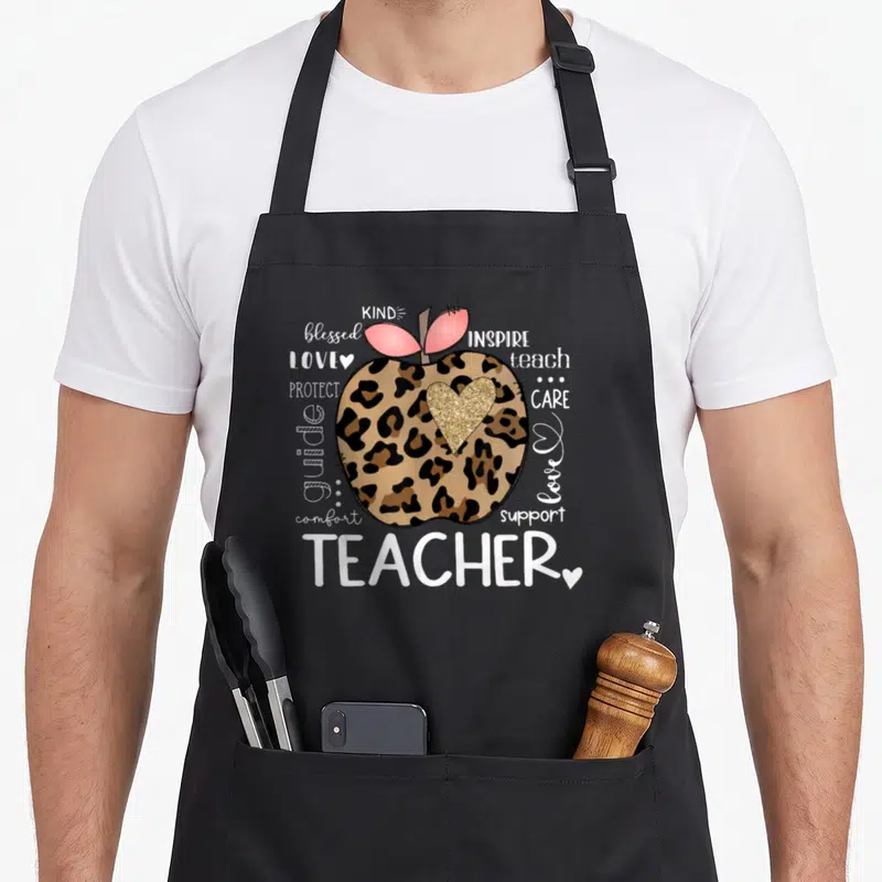 Teacher apple apron - Leopard print apple with gold heart surrounded by teacher appreciation words — shown on a black cotton canvas apron against a white background