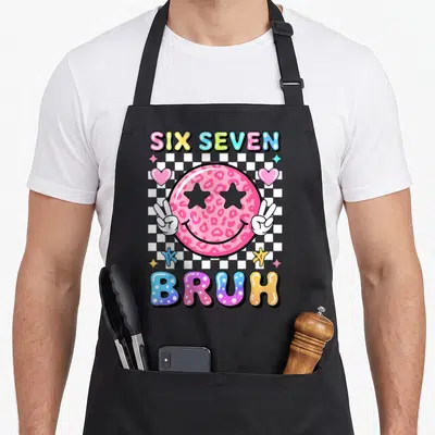 Face meme apron - Pink leopard print smiley face with star eyes and peace signs over checkerboard with SIX SEVEN BRUH — shown on a black cotton canvas apron against a white background