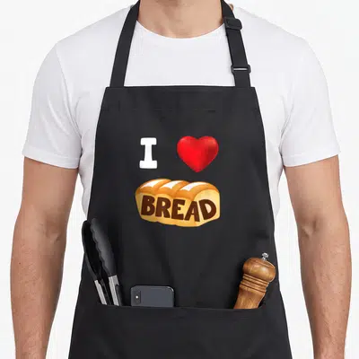 Gluten bread apron - White I, red heart, and golden brown bread loaf with brown text — shown on a black cotton canvas apron against a white background