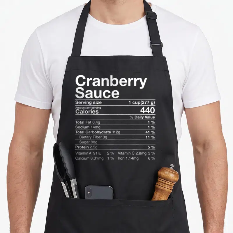 Cranberry thanksgiving day aprons - White nutrition facts label for Cranberry Sauce showing 440 calories and 88g sugar — shown on a black cotton canvas apron against a white background