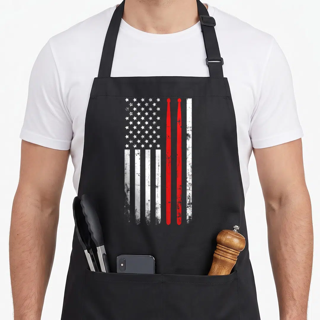 Drum american flag apron - Vertical distressed USA flag with two red drumsticks replacing right-side stripes — shown on a black cotton canvas apron against a white background