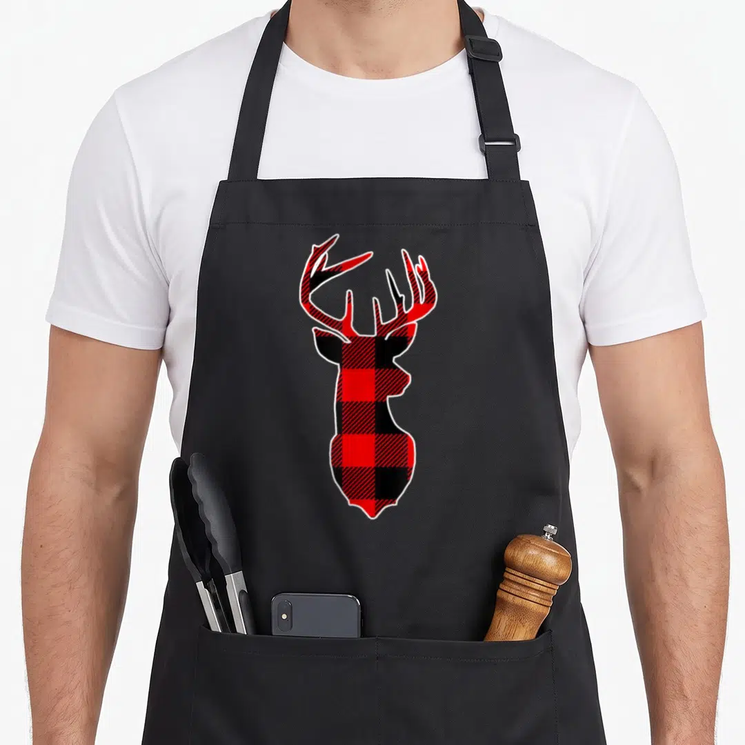 Deer reindeer apron - Red and black buffalo plaid deer head silhouette with white outline border — shown on a black cotton canvas apron against a white background