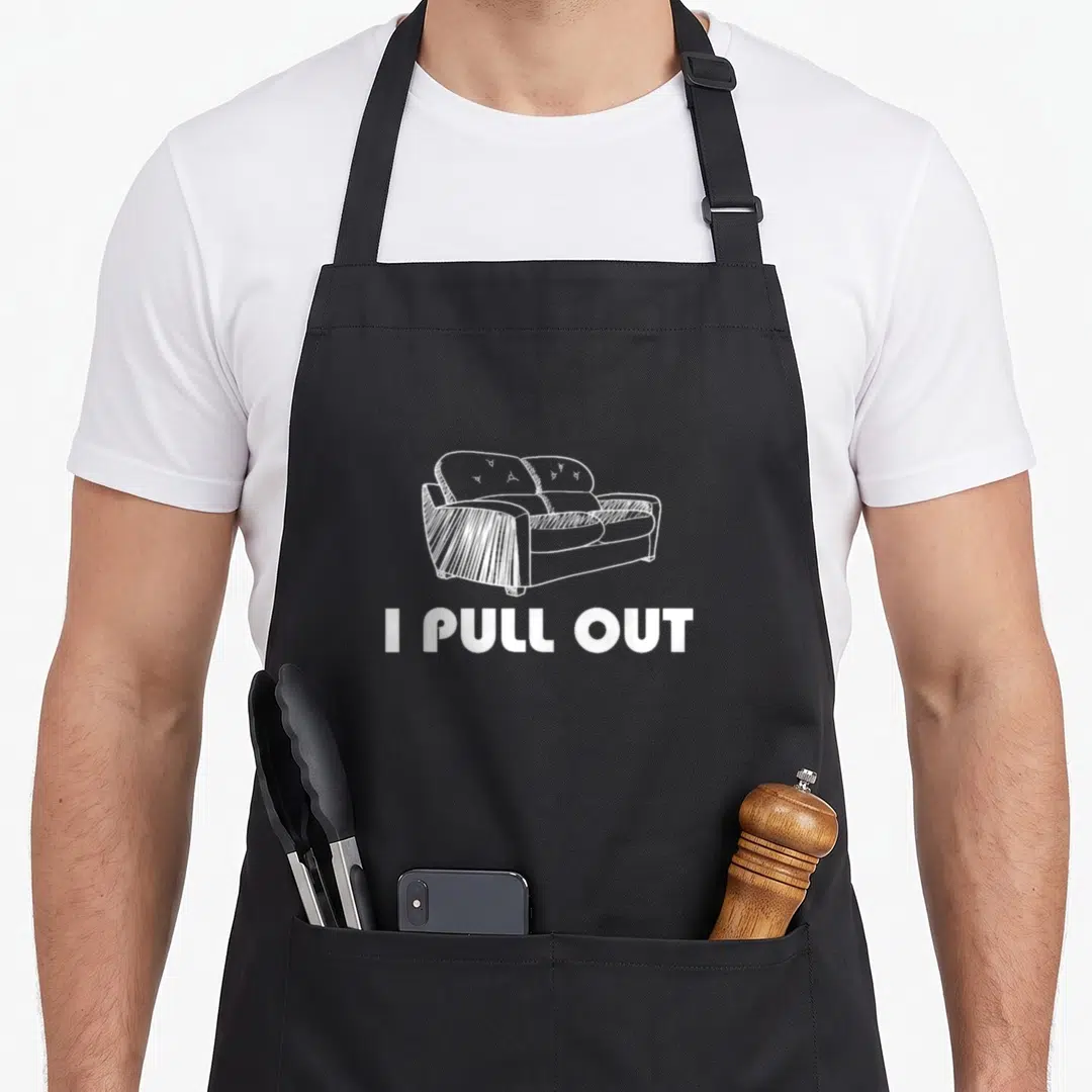 Pull dirty lover apron - White line drawing of a sofa above the text I PULL OUT on a dark background — shown on a black cotton canvas apron against a white background