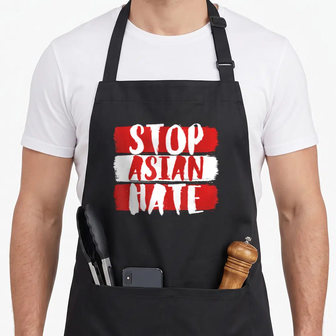 Hate asian apron - STOP ASIAN HATE text on red and white brush strokes — shown on a black cotton canvas apron against a white background