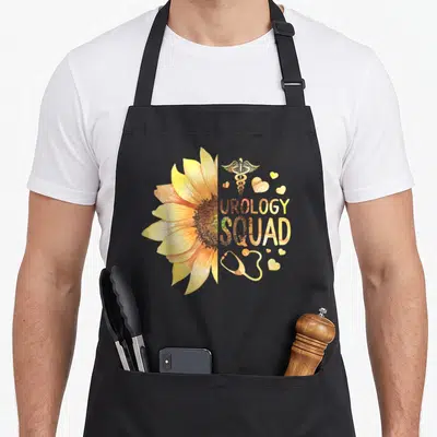 Urology nurse apron - Split sunflower with caduceus, stethoscope, hearts, and UROLOGY SQUAD text in yellow gold brown — shown on a black cotton canvas apron against a white background